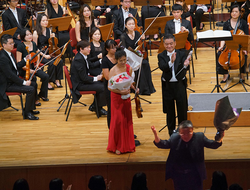 Professor Lee Sun-Don (Lower right) greeting the audience, waving the dedicated flowers received and forwarded by Music Director and Conductor Liao Jiahong. 